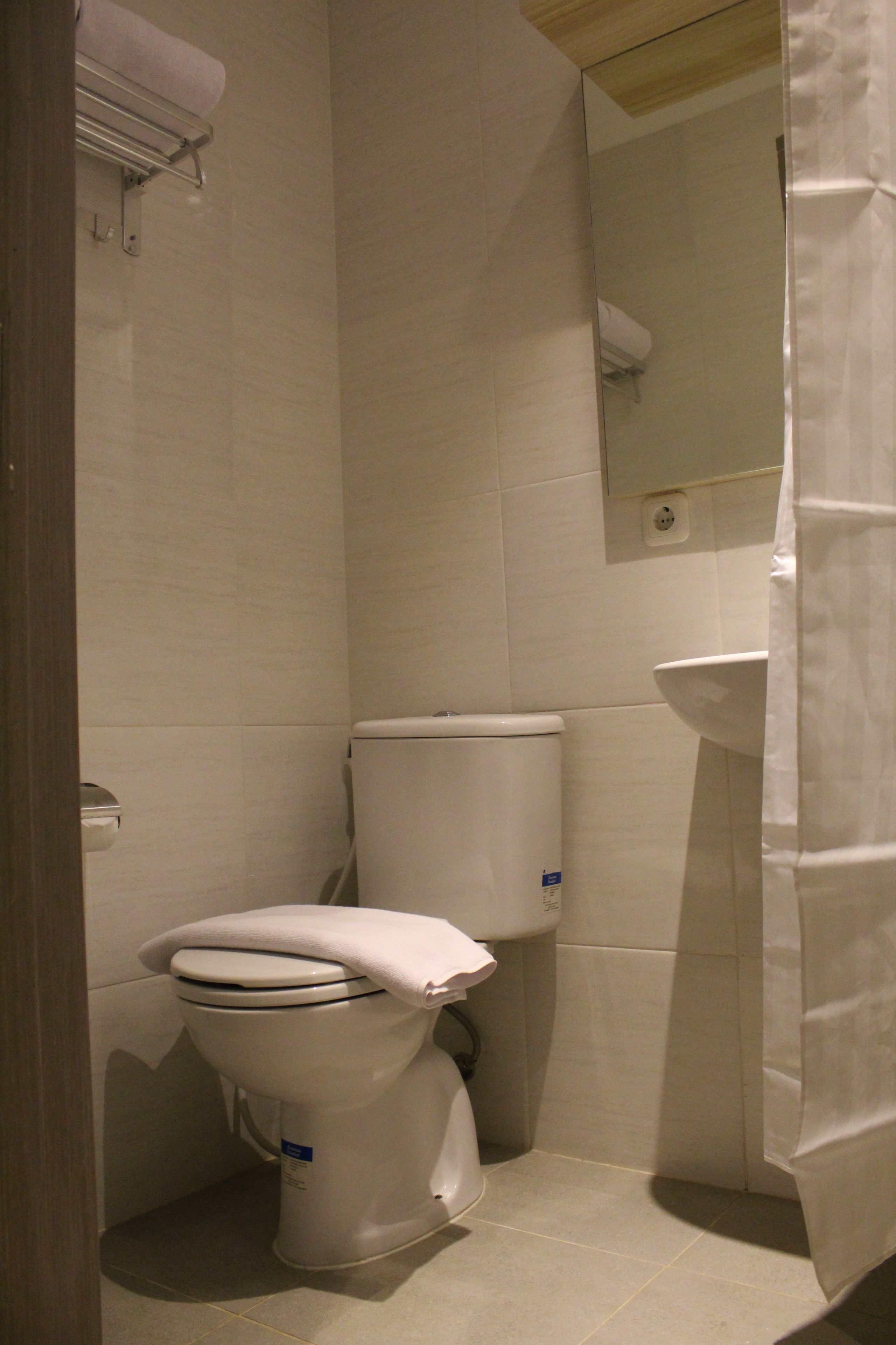 A small, compact bathroom with a toilet, sink, and mirror.
