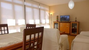 Ein Zimmer mit Esstisch, Stühlen, Fernseher und Schrank.