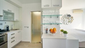 A modern kitchen with white cabinetry, a built-in oven, and a countertop with a fruit bowl. - Sun Lover`s Paradise.  Private rooftop seaview terrace, amazing romantic holiday (Marbella)