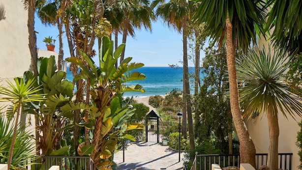 A pathway leading to a beach with palm trees and a gazebo. - Sun Lover`s Paradise.  Private rooftop seaview terrace, amazing romantic holiday (Marbella)