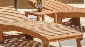 Zona relax all'aperto con sedute in legno, vasca idromassaggio e una bottiglia di vino.