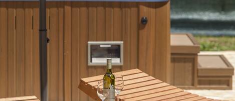 Un espace extérieur aménagé en bois avec des sièges, un jacuzzi et une bouteille de vin.