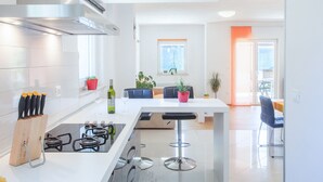 Una cucina moderna con isola centrale, sgabelli da bar e zona pranzo con tavolo e sedie.