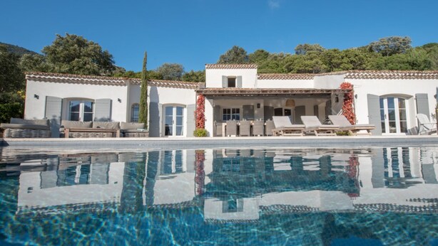 Eine Poolvilla mit klarem Pool, einer überdachten Terrasse mit Liegestühlen und einem Bergpanorama im Hintergrund.