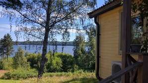 Eine Holzhütte mit Blick auf einen See und umgebende Grünflächen.