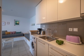 Une cuisine compacte équipée d’un lave-linge, d’un grille-pain et d’un évier.