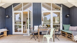 Un espacio exterior acogedor con mesa de madera, sillas y un banco con cojines.