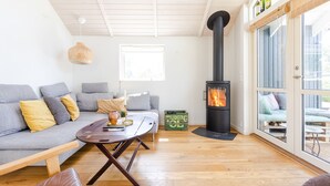 Una sala de estar moderna con un sofá, una mesa de centro, una chimenea y un ventanal grande.
