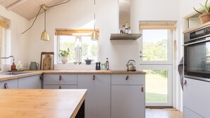 Una cocina moderna con armarios blancos, encimeras de madera e iluminación colgante.
