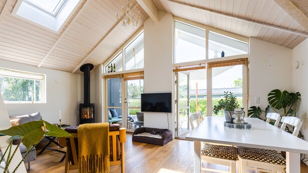 Un salón espacioso con suelo de madera, una mesa blanca grande y una zona de estar cómoda.