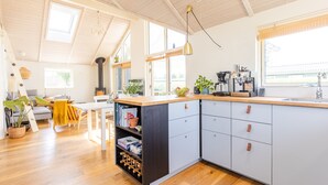 Una cocina moderna con una isla de madera, ventanas amplias y un comedor con mesa y sillas.