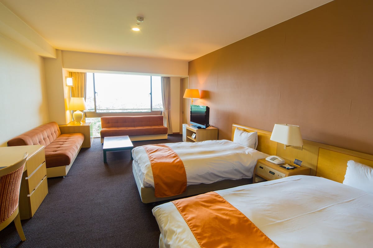 Habitación de hotel con dos camas, un sofá, un escritorio y una televisión.