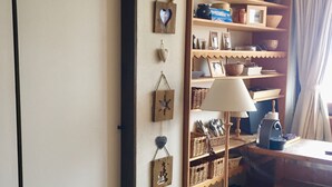 Una stanza con una scrivania in legno, una lampada, uno scaffale con diversi oggetti e una parete decorata con cuori.