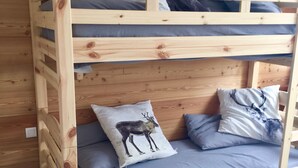 Un letto a castello in legno con materasso blu e cuscini decorativi, tra cui uno con una cerva.