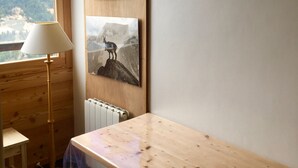 Una piccola stanza in legno con un tavolo, una lampada e due quadri appesi al muro.