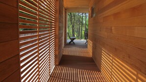 A wooden interior corridor with a slatted wall and a bench at the end. - Contemporary house with spectacular view of the forest (Notre-Dame-De-Monts)
