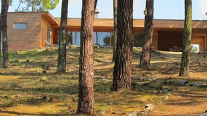 A modern wooden building with a large window and a covered outdoor area. - Contemporary house with spectacular view of the forest (Notre-Dame-De-Monts)