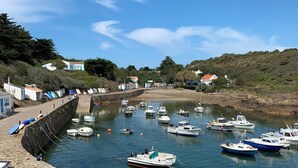 A harbor with boats docked along the shore, a stone wall, and buildings in the background. - Contemporary house with spectacular view of the forest (Notre-Dame-De-Monts)