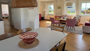 A modern living room with a dining area, large windows, and a view of the outdoors. - Vacation apartment at Obstgut Willmann, quiet location with a view of Lake Constance (Kressbronn)