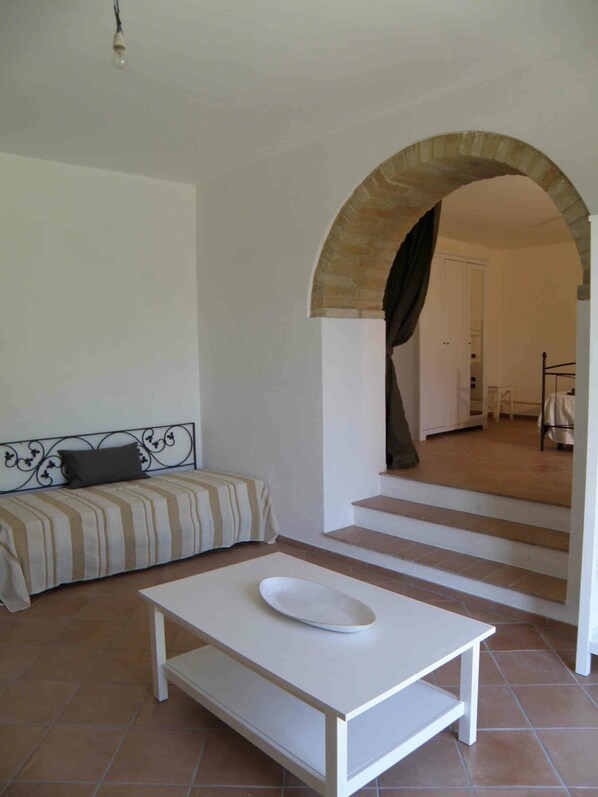 Une pièce comprenant un canapé, une table blanche et un escalier menant à un autre espace.