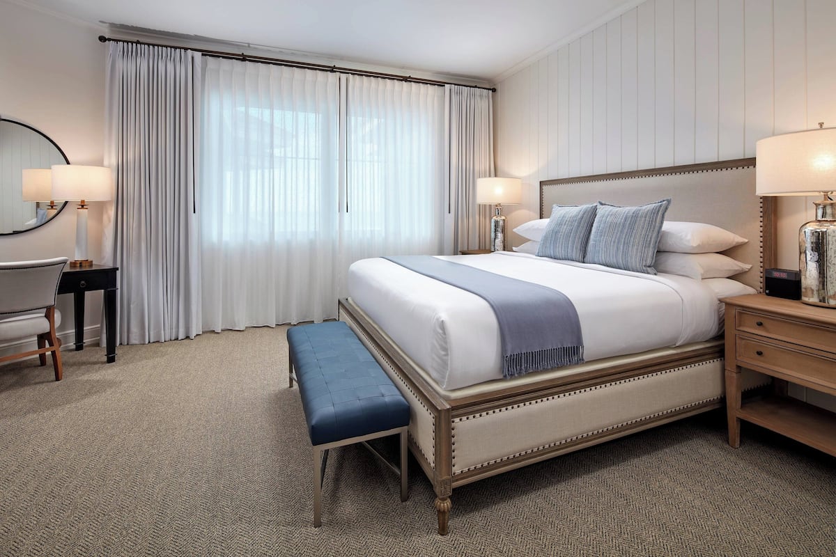 Une chambre d’hôtel bien aménagée, avec un grand lit, un banc, un bureau et une chaise.