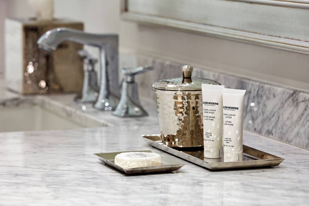 Un meuble-lavabo de salle de bain avec un plan de toilette en marbre, un porte-savon et deux flacons de lotion.
