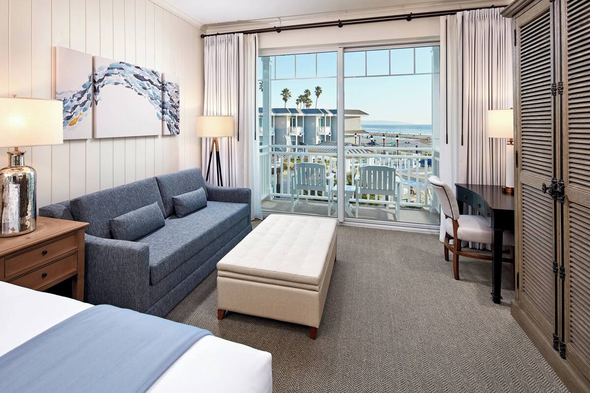 Une chambre d’hôtel avec un balcon, un canapé, un lit et un bureau.