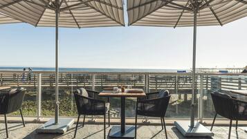 Une terrasse avec des sièges extérieurs, une table et une vue sur l’océan.