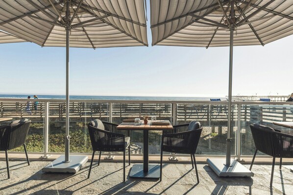 Una terraza con mobiliario exterior, una mesa y vistas al océano.