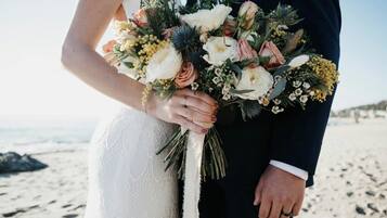 Un couple tenant un bouquet de fleurs sur une plage.