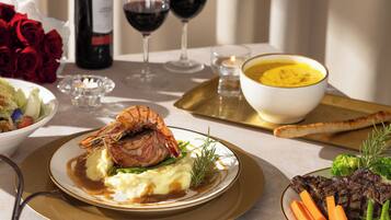 Ett elegant matbord med en mängd olika rätter, inklusive en biff, potatismos och grönsaker. På bordet står vinglas och en vinflaska.
