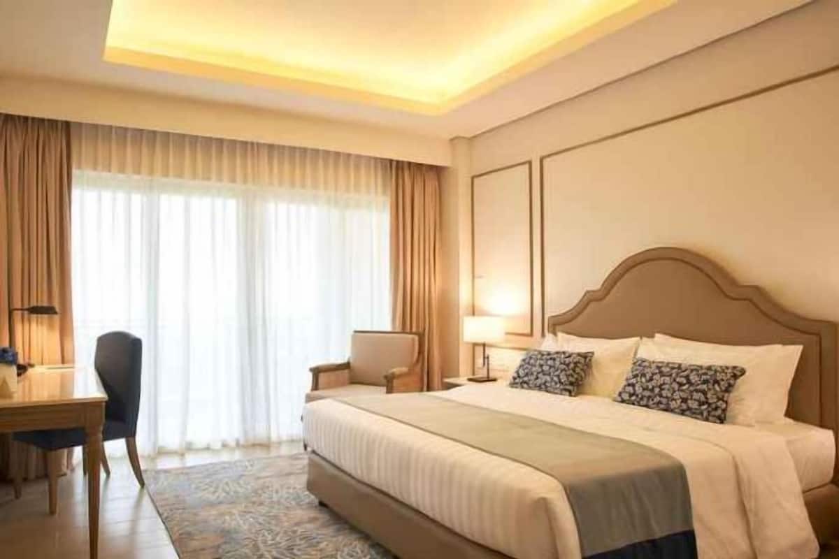 A hotel room with a large bed, a desk, and a chair.