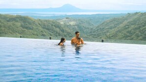 Una pareja en una piscina infinita con vistas a un paisaje montañoso.