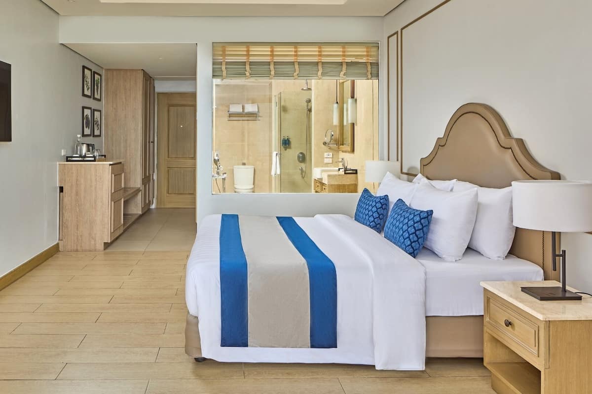 A hotel room with a large bed, bedside tables, a desk, and a view of the bathroom.