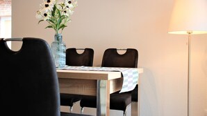 A dining table with a vase of flowers, two chairs, a clock on the wall, and a floor lamp. - Apartment / Fitter Eal at the Thülsfelder dam (Friesoythe)