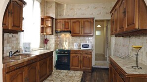 A kitchen with wooden cabinets, a stove, a microwave, and a coffee maker.