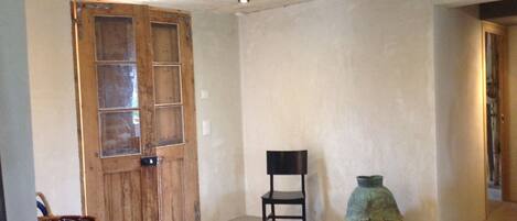 A room with a wooden door, a black chair, and a ceramic vase.