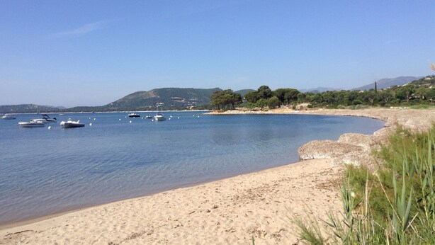 A beach with boats, clear water, and a hilly landscape in the background. - House Beachfront in Pinarello Bay. (Zonza)