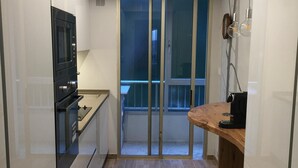 Een moderne keuken met een inbouwoven, een houten aanrechtblad en een schuifdeur naar een balkon.