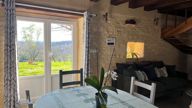A dining area with a table set for two, a potted plant, and a view of greenery outside. - *** Perigord cottage with pool (Archignac)