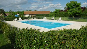 A rectangular swimming pool with a white deck, surrounded by green hedges and white lounge chairs. - Spring nature and sport in 'fleur de sologne' (Souvigny-En-Sologne)