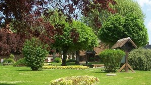 A well-maintained garden with a wooden birdhouse, neatly trimmed hedges, and a variety of trees. - Spring nature and sport in 'fleur de sologne' (Souvigny-En-Sologne)