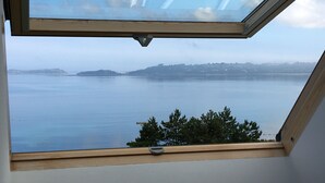A skylight window with a view of a calm body of water and distant landforms. - VERY COMFORTABLE HOUSE EXCEPTIONAL VIEW SEA - GRAND GARDEN CLOS 8 people  (Trédrez-Locquémeau)