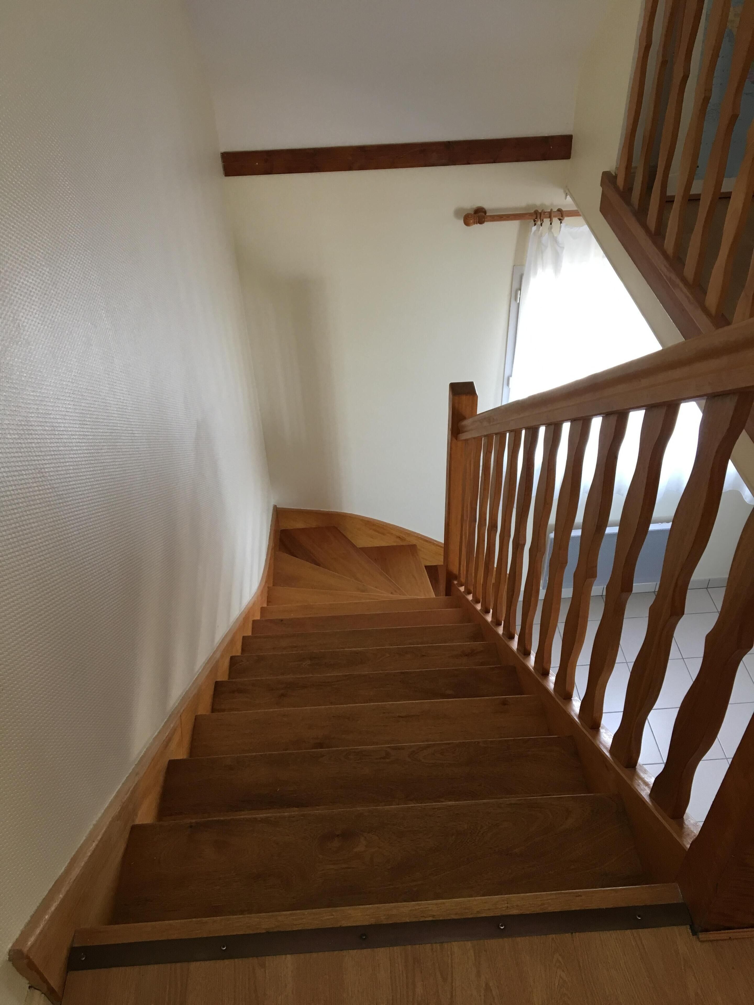 A wooden staircase with a handrail and a wooden banister.