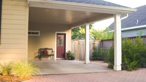 A covered porch with a bench and potted plants, a red door, and a brick pathway leading to the house. - Walk .4 Miles to Texas A&M Campus and Aggie Park, Private Entry /Covered Parking (College Station)