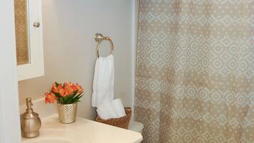 Een bad/douchecombinatie, een haardroger, handdoeken