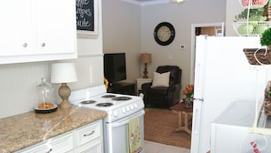 A kitchen with white cabinets, a stove, and a refrigerator. There is a clock on the wall and a chair in the background. - Walk .4 Miles to Texas A&M Campus and Aggie Park, Private Entry /Covered Parking (College Station)