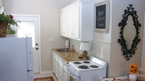 A kitchen with white cabinets, a stove, a sink, and a chalkboard sign. - Walk .4 Miles to Texas A&M Campus and Aggie Park, Private Entry /Covered Parking (College Station)