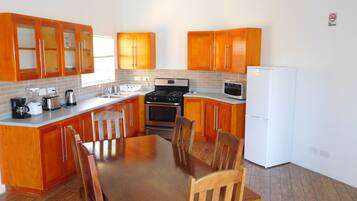 A kitchen with wooden cabinets, a stove, a microwave, and a dining table with chairs.