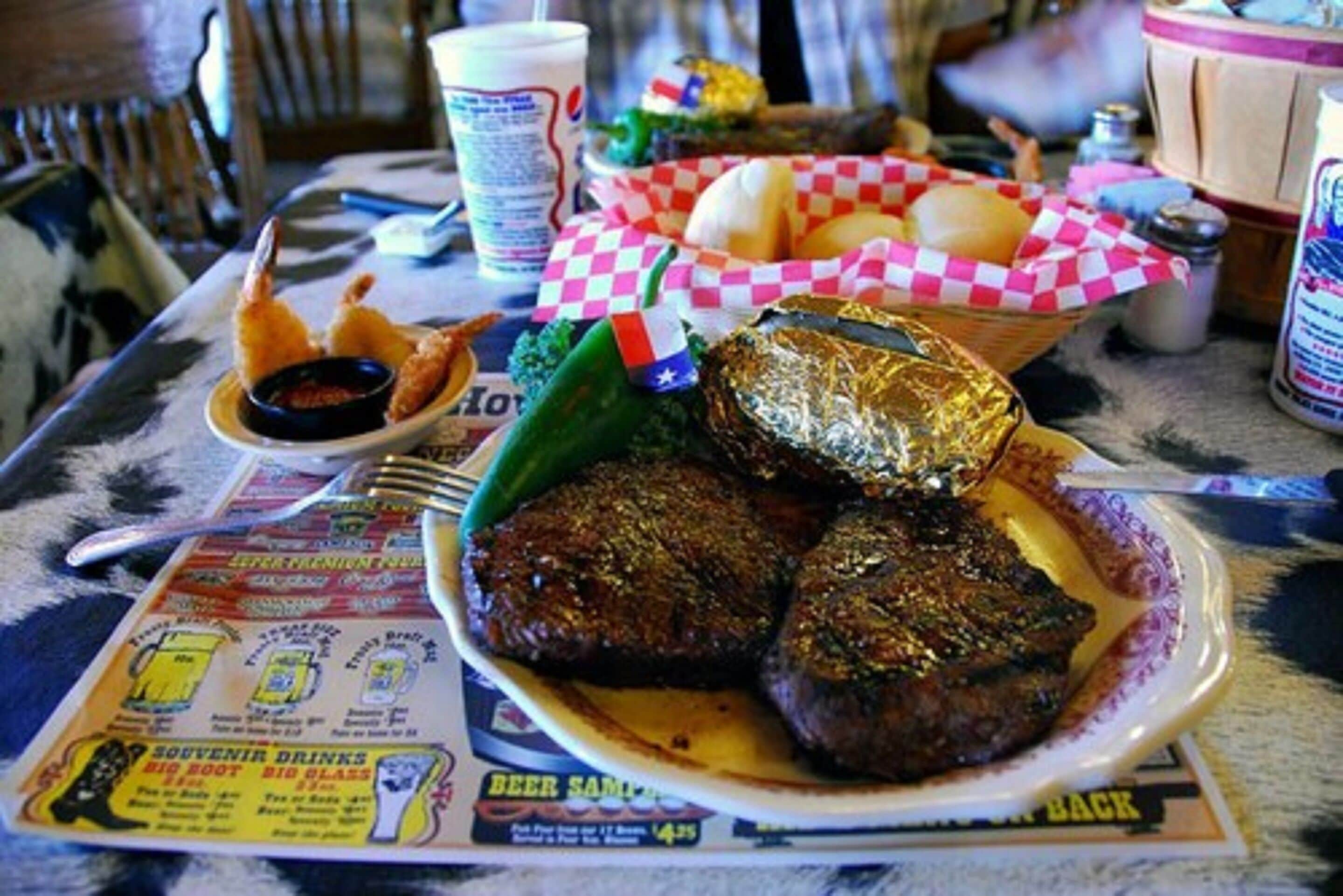 A table with a plate of food, a basket of rolls, and a menu.